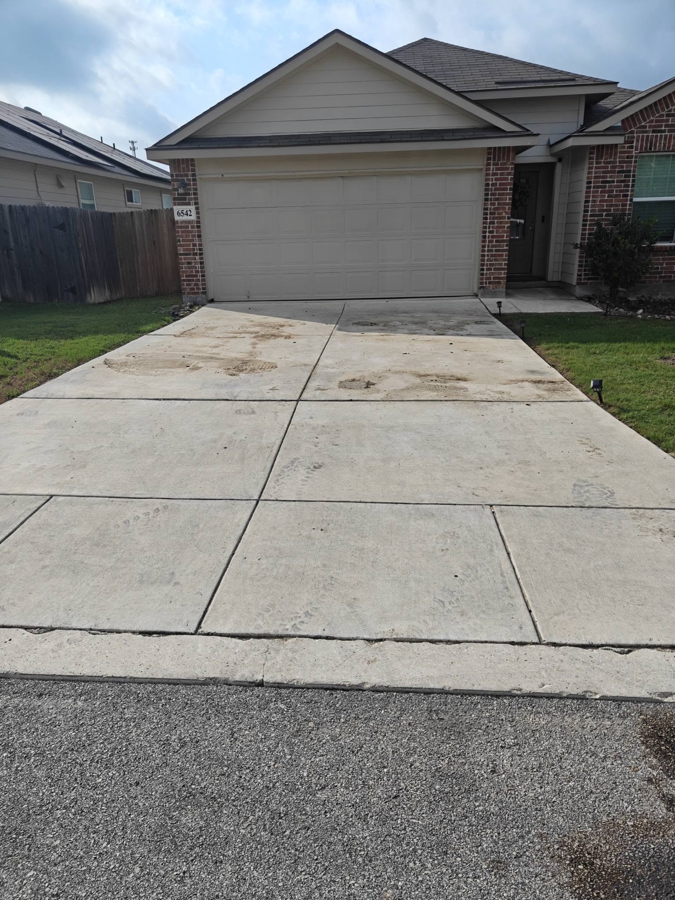 Driveway before Titan Wash concrete pressure washing with dirt and tire marks
